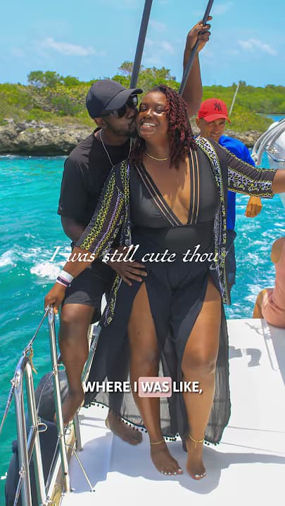 A man kisses a smiling woman's cheek on a boat with vibrant turquoise water.